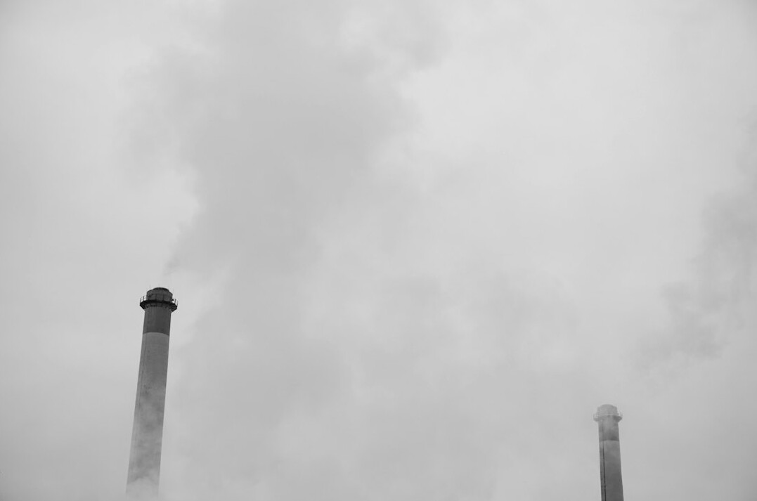 Industrial factory chimneys with smoke against grey sky